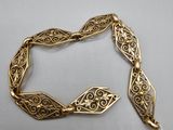 gros plan d'un bracelet en or sur une surface blanche