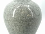 a gray vase that is sitting on a white surface