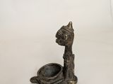 a small bronze statue of a cat with a bowl in its mouth