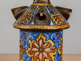 a blue and orange vase with a wooden handle on a table