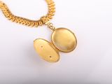 a close up of a gold locke necklace with a chain