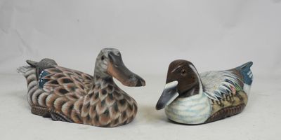 deux canards en céramique assis l'un à côté de l'autre sur une surface blanche