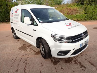 La camionnette blanche est garée sur le parking, près des buissons.