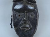 une image représentant un masque noir accroché à un mur