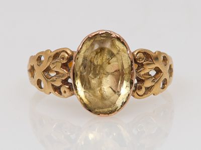 un gros plan d'une bague en or ornée d'un visage de femme