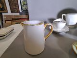 a white pitcher sitting on top of a table next to a plate