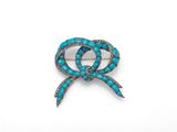 une broche en forme de nœud, en turquoise et diamants