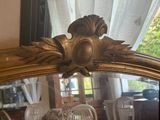 un grand miroir avec un cadre doré sur lequel est représenté un oiseau
