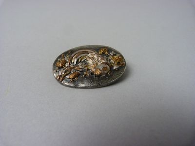 BROCHE en shakudō à décor d'un oiseaux de paradis et de végé…