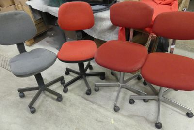quatre chaises de bureau montées sur roulettes, disposées dans une pièce avec d’autres meubles de bureau