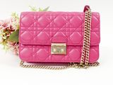 pink quilted purse with chain and flower on white background