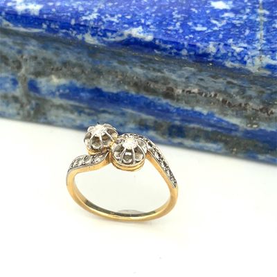 a close up of a diamond and gold ring on a blue stone