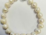 un gros plan d'un bracelet de perles blanches posé sur une surface blanche