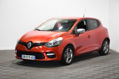 La voiture orange est garée sur un sol à damier dans une pièce.