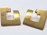 deux paires de boucles d'oreilles carrées couleur or sur un fond blanc