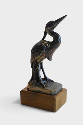 an image of a bronze statue of a bird on a wooden base