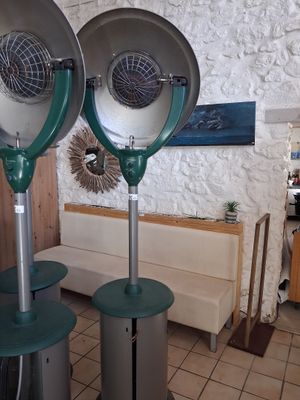 two metal fans sitting on top of tables in a room