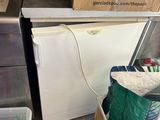 un petit réfrigérateur au milieu d'une cuisine où il y a beaucoup de cartons par terre