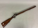 un fusil avec une poignée en bois sur une surface blanche