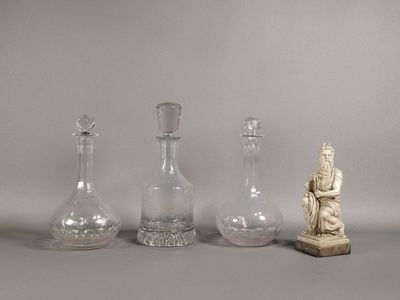 quatre vases en verre et une statue représentant une femme assise, posés sur une table