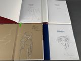 several open books with drawings on them sitting on top of a table