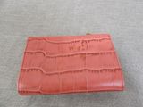 an orange crocodile skin wallet on a gray surface
