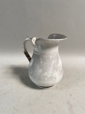 un pichet blanc posé sur une table, avec une cuillère à l'intérieur