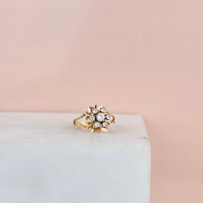 une bague de fiançailles en or ornée d'un motif floral, posée sur un bloc de marbre blanc