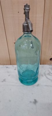 a blue glass bottle with a metal spout sitting on a table