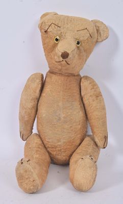 un ours en peluche marron assis sur une surface blanche