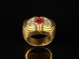 a close up of a gold ring with a red stone in it