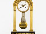 une horloge posée sur un support sur une surface blanche