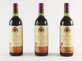 trois bouteilles de vin rouge posées l'une à côté de l'autre sur une surface blanche