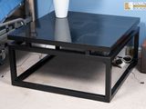 une table basse noire sur laquelle est posé un vase blanc
