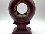 a red vase with a hole in it on a white surface