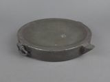 a silver plate with a handle on a white surface