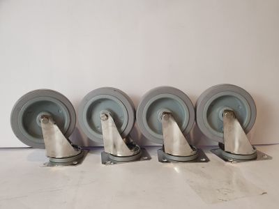 quatre chaises de couleur grise sont alignées contre un mur blanc