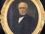 a portrait of a man in a suit and bow tie in a gold frame