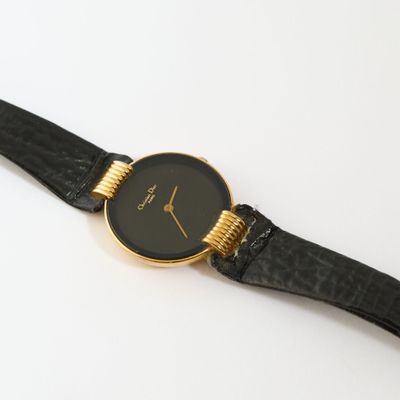 un gros plan d'une montre noire et dorée posée sur une surface blanche