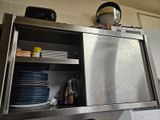 un placard en acier inoxydable dans la cuisine, avec de la vaisselle posée sur le plan de travail