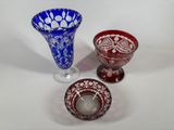 three different colored glass vases sitting next to each other on a white surface