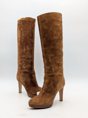 un gros plan sur une paire de bottes en daim marron sur fond blanc