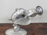 une statue en argent représentant un oiseau, posée sur un socle