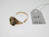 une photo montrant une bague en or et une étiquette posées sur une table blanche
