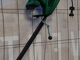 une pancarte fixée sur le mur d'un immeuble, à laquelle est accrochée une tondeuse à gazon verte