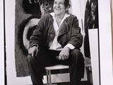 black and white photograph of a man sitting on a bench in front of a painting