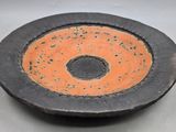 un bol noir et orange avec un trou au milieu