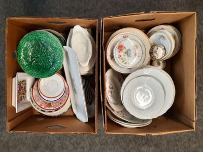 two boxes with plates and bowls in them on the floor