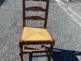 an old wooden chair sitting in a parking lot next to a chain link fence