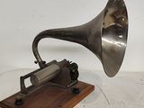 un vieux gramophone argenté posé sur un socle en bois, avec un fond blanc